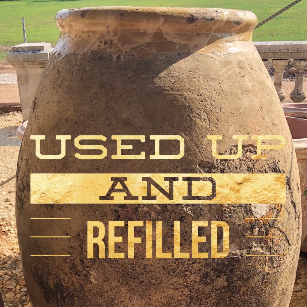 A large brown vase with the words used up and refilled on it.