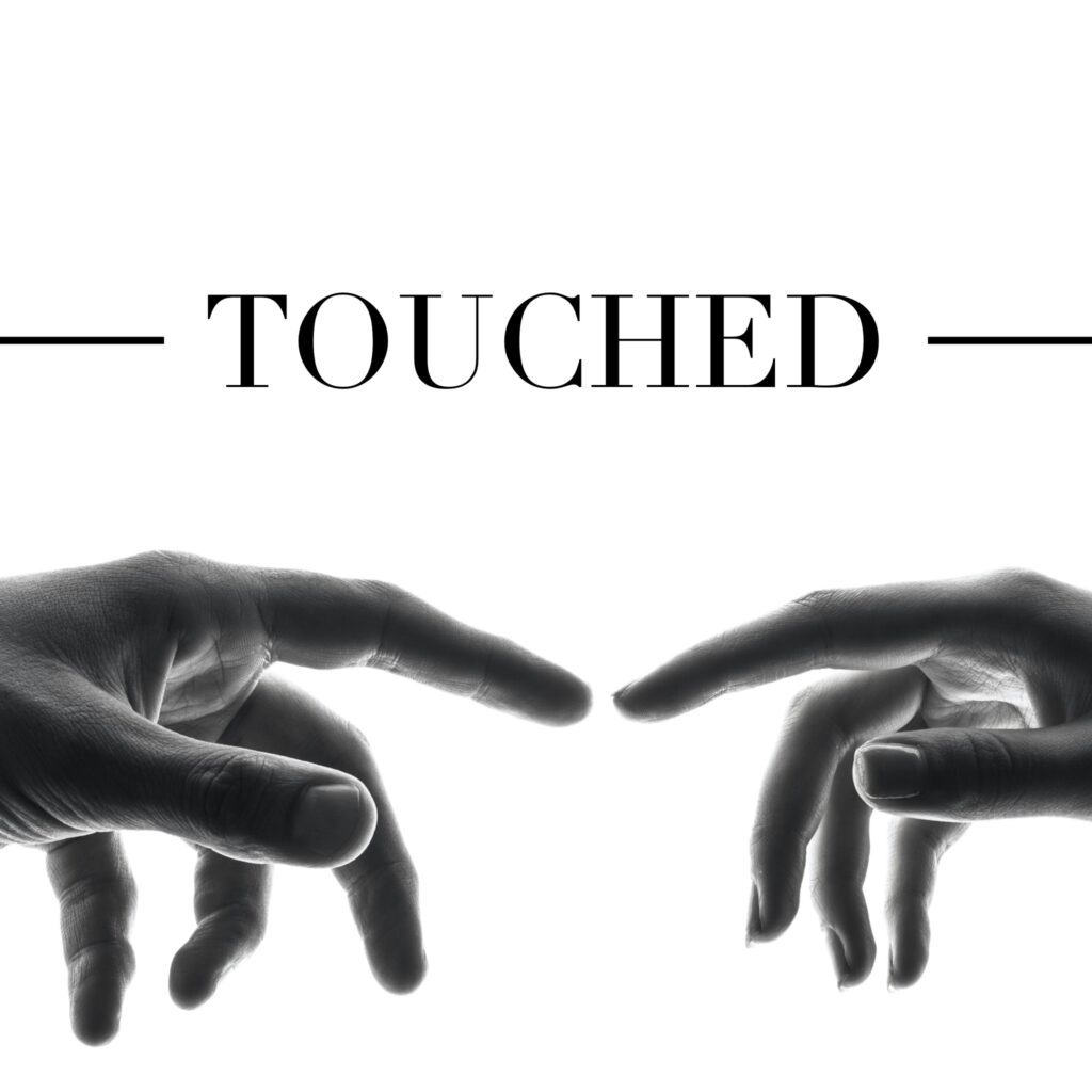A black and white photo of two hands touching one another.