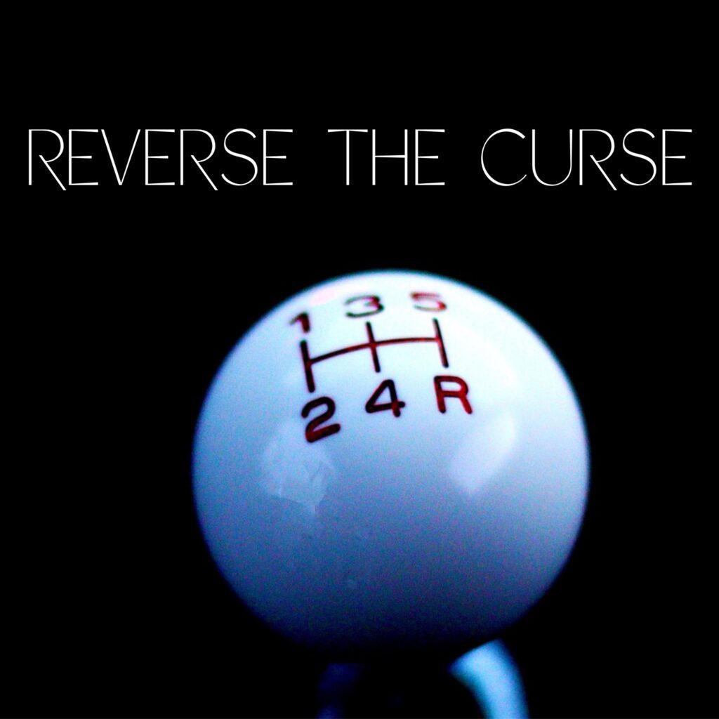 A close up of an automatic shift knob with the words " reverse the curse ".