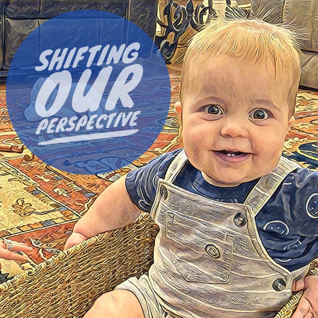A baby sitting on the floor with a blue sign in front of him.