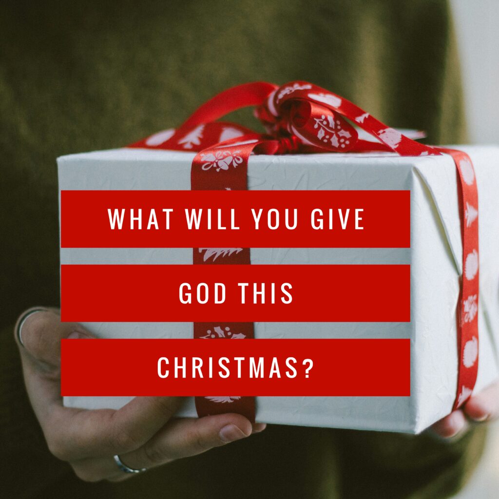 A person holding a gift box with the words " what will you give god this christmas ?" written on it.