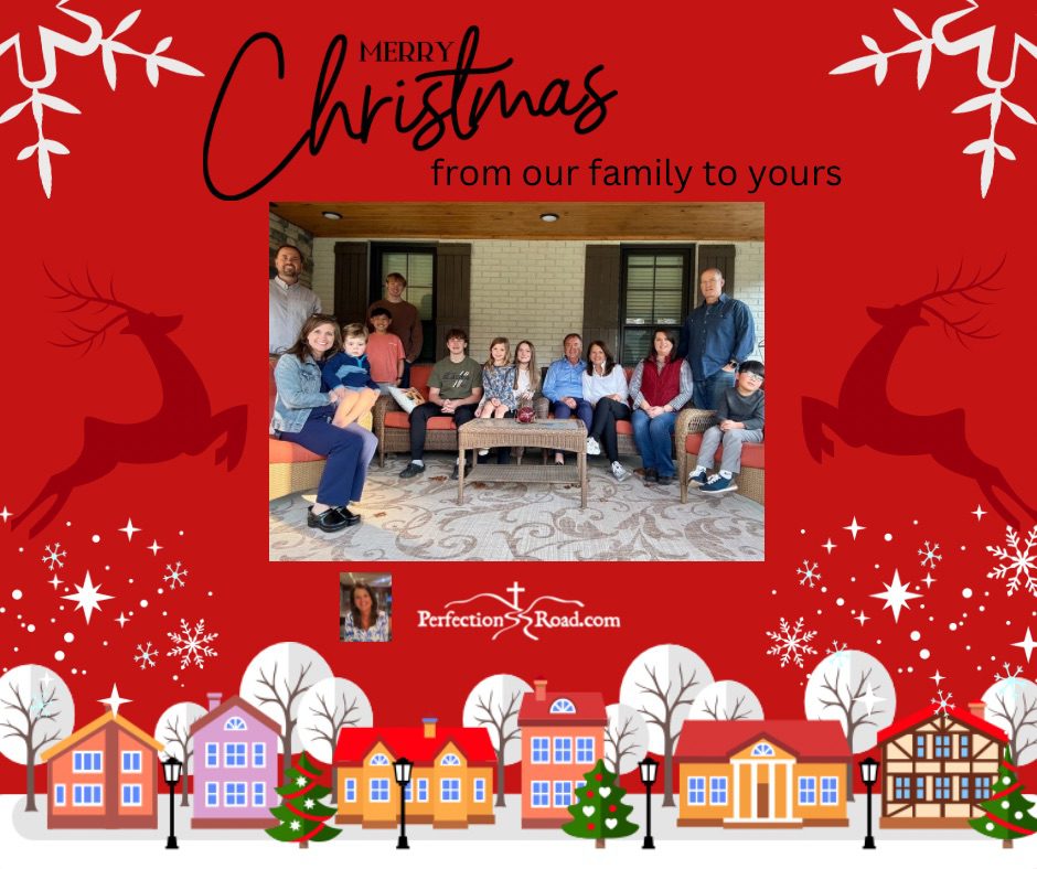 A family sitting on the ground in front of christmas decorations.